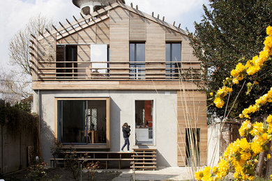 Cette photo montre une grande façade de maison de ville beige tendance en bois à un étage avec un toit à deux pans et un toit mixte.
