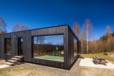 Cette image montre une façade de maison noire asiatique en bois avec un toit plat.