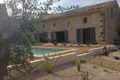 Example of a tuscan white two-story stone house exterior design in Montpellier with a hip roof and a tile roof