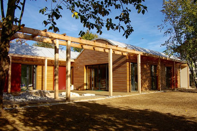 Idée de décoration pour une grande façade de maison marron minimaliste en bois de plain-pied avec un toit de Gambrel et un toit en métal.