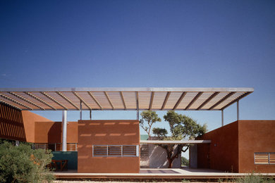 Diseño de fachada roja mediterránea de tamaño medio de una planta con revestimientos combinados y tejado plano