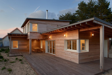 Réalisation d'une grande façade de maison beige marine en bois à un étage avec un toit plat et un toit mixte.