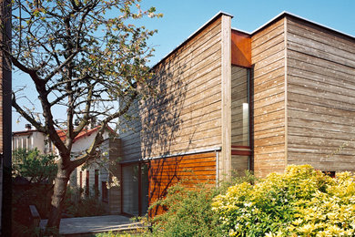 Cette image montre une façade de maison design en bois de taille moyenne et à un étage avec un toit plat.