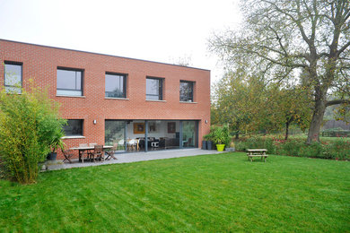 Inspiration for a medium sized and red contemporary two floor brick house exterior in Lille with a flat roof.