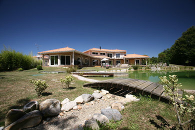 Aménagement d'une façade de maison beige méditerranéenne de taille moyenne et à un étage avec un toit à quatre pans.