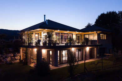 Cette image montre une grande façade de maison marron design en bois à un étage avec un toit à quatre pans et un toit en tuile.