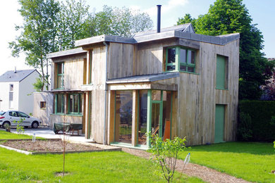 Cette image montre une façade de maison marron design en bois à un étage avec un toit en métal.