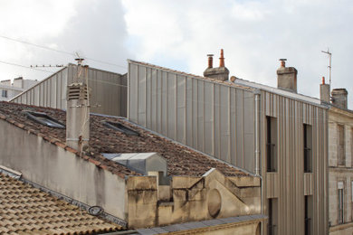 На фото: большой, трехэтажный, серый таунхаус в современном стиле с облицовкой из металла, двускатной крышей и черепичной крышей с
