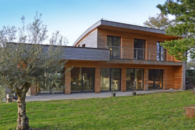 Modelo de fachada de casa beige contemporánea grande de dos plantas con revestimiento de madera