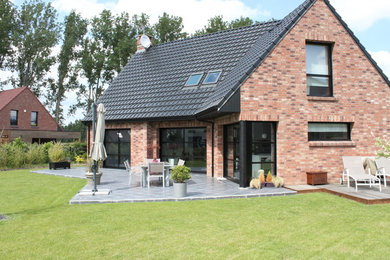 Diseño de fachada de casa roja contemporánea de tamaño medio de dos plantas con revestimiento de ladrillo, tejado a dos aguas y tejado de teja de barro