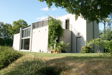 Modelo de fachada gris contemporánea de tres plantas con tejado plano