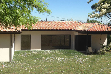 Cette photo montre une façade de maison blanche tendance en brique de taille moyenne et de plain-pied avec un toit à quatre pans et un toit en tuile.