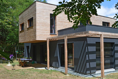 Modelo de fachada de casa negra actual de tamaño medio de dos plantas con revestimiento de madera y tejado plano