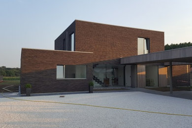 Cette photo montre une grande façade de maison marron tendance en brique à un étage avec un toit plat.