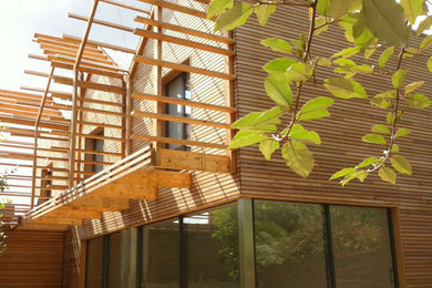 Cette image montre une très grande façade de maison beige design en bois à un étage avec un toit à deux pans et un toit en métal.