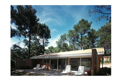 Imagen de fachada de casa contemporánea pequeña de una planta con revestimiento de madera, tejado a dos aguas y techo verde
