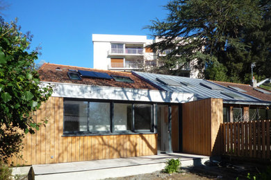 Cette photo montre une petite façade de maison de ville grise moderne en bois de plain-pied avec un toit plat.