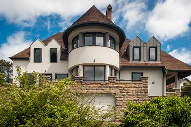 Cette photo montre une façade de maison beige chic de taille moyenne et à un étage avec un revêtement mixte et un toit à quatre pans.