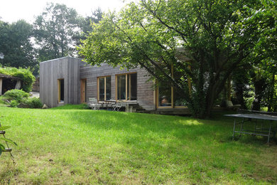 Modelo de fachada gris actual de tamaño medio de una planta con revestimiento de madera y tejado plano