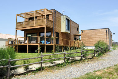 Foto de fachada de casa marrón campestre grande de dos plantas con revestimiento de madera, tejado plano y tejado de metal