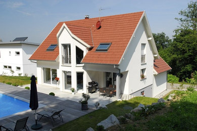 Aménagement d'une grande façade de maison beige moderne en brique à niveaux décalés avec un toit à deux pans et un toit en tuile.