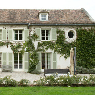 Cette image montre une très grand façade de maison blanche rustique à deux étages et plus avec un toit à deux pans et un toit en tuile.