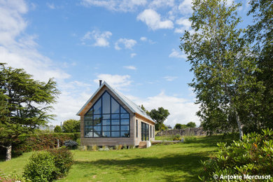 Idée de décoration pour une façade de maison grise nordique en bois de taille moyenne et à un étage avec un toit à deux pans et un toit en métal.