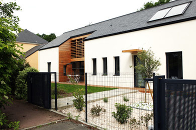 Cette photo montre une façade de maison blanche tendance de taille moyenne et à un étage avec un revêtement mixte et un toit à deux pans.