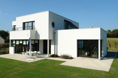 Aménagement d'une grande façade de maison blanche moderne en béton à un étage avec un toit plat et un toit mixte.
