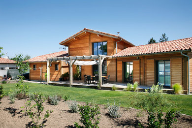 Réalisation d'une façade de maison marron chalet en bois de taille moyenne et à un étage avec un toit à deux pans.