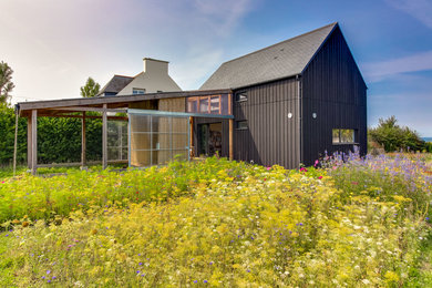 Ejemplo de fachada negra de estilo de casa de campo pequeña de dos plantas con revestimiento de madera