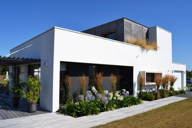 Aménagement d'une façade de maison blanche contemporaine à un étage avec un revêtement mixte et un toit plat.
