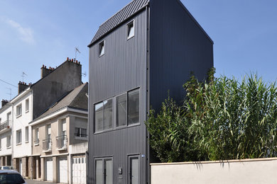 Aménagement d'une façade de maison de ville métallique et grise industrielle de taille moyenne et à deux étages et plus avec un toit à deux pans et un toit en métal.
