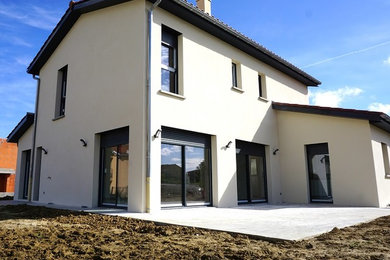 Cette photo montre une façade de maison beige tendance à un étage et de taille moyenne avec un toit à deux pans.