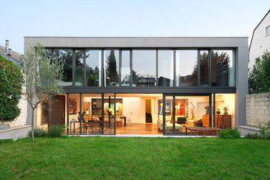 Inspiration pour une grande façade de maison de ville grise minimaliste en verre à un étage avec un toit plat et un toit en métal.