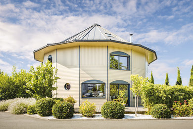 Idée de décoration pour une grande façade de maison beige design à un étage avec un toit à quatre pans et un toit en métal.