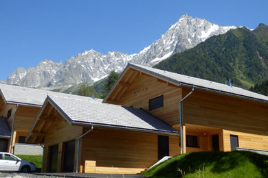 Aménagement d'une façade de maison beige campagne en bois de taille moyenne avec un toit à deux pans et un toit en tuile.