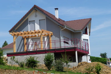 Inspiration pour une façade de maison grise design en bois à deux étages et plus avec un toit à deux pans et un toit en tuile.