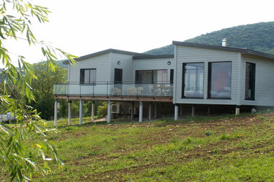Idée de décoration pour une façade de maison grise design en bois avec un toit en métal.