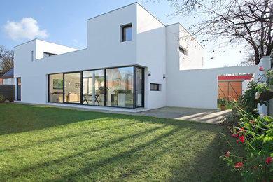 Idée de décoration pour une façade de maison blanche design en stuc à un étage avec un toit plat.