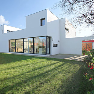 Idée de décoration pour une façade de maison blanche design à un étage avec un revêtement en stuc et un toit plat.