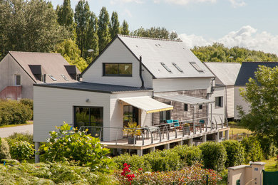 Inspiration pour une façade de maison blanche design en bois à un étage avec un toit à deux pans.