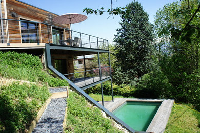 Ejemplo de fachada de casa grande de tres plantas con revestimiento de madera, tejado plano y techo verde