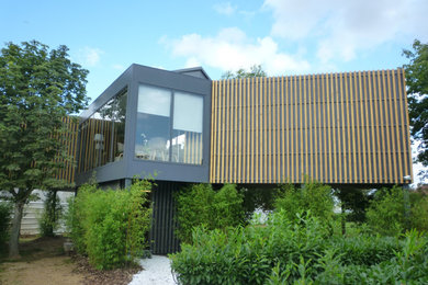 Réalisation d'une façade de maison grise design de taille moyenne et à un étage avec un revêtement mixte, un toit plat et un toit en métal.