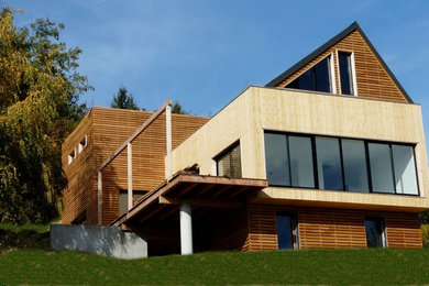 Ejemplo de fachada de casa marrón contemporánea grande de tres plantas con revestimiento de madera y tejado a dos aguas