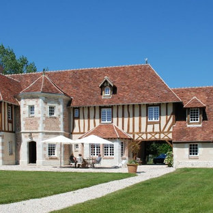 Idée de décoration pour une grand façade de maison beige champêtre à deux étages et plus avec un revêtement mixte et un toit à quatre pans.