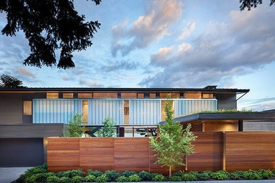 Diseño de fachada marrón contemporánea grande de tres plantas con revestimiento de madera y tejado plano