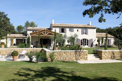 Aménagement d'une grande façade de maison blanche méditerranéenne à un étage avec un toit à deux pans.