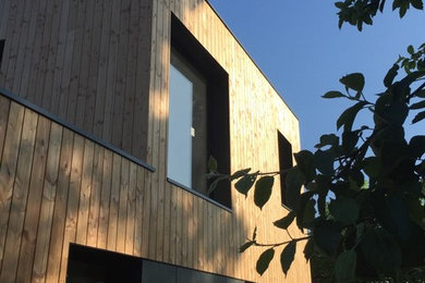 Aménagement d'une petite façade de maison grise contemporaine en bois à un étage avec un toit plat.