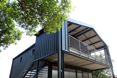 Exemple d'une façade de maison métallique et grise industrielle de taille moyenne et à un étage avec un toit à deux pans et un toit en métal.